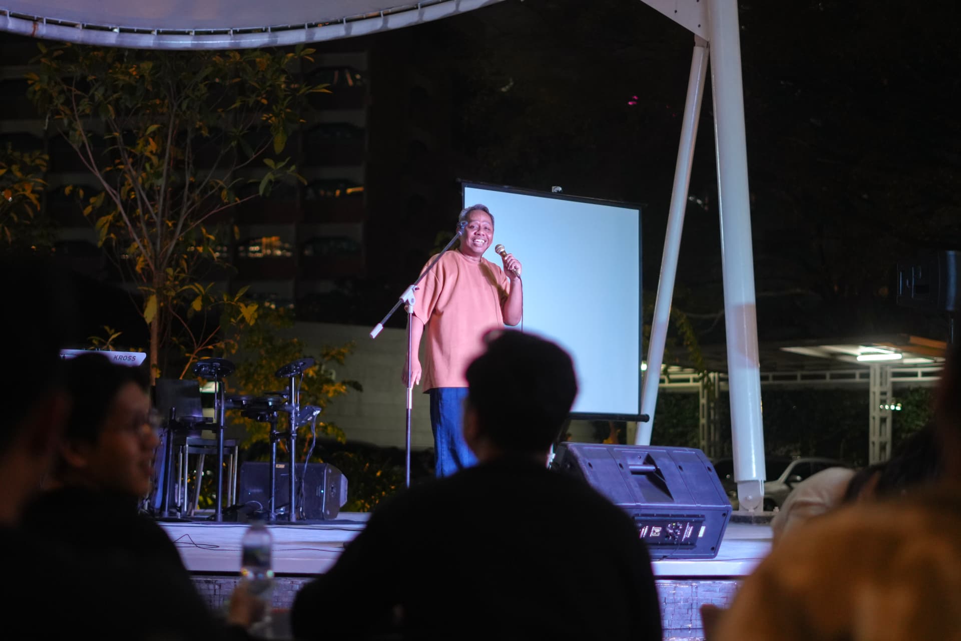 Performer holding the mic on an outdoor stage at night