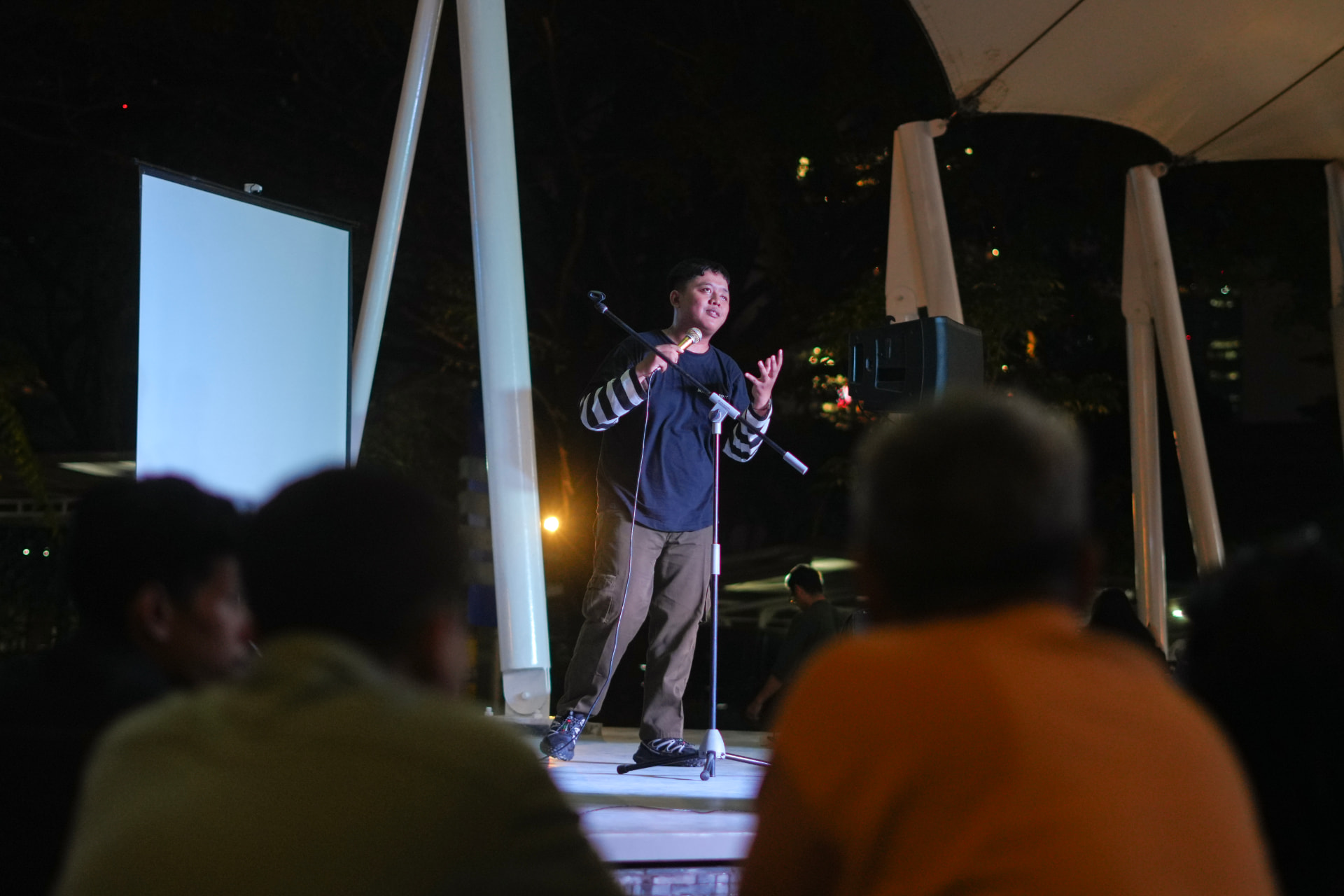 A comedian performing stand-up on stage at an ARC Golden Mic open mic night