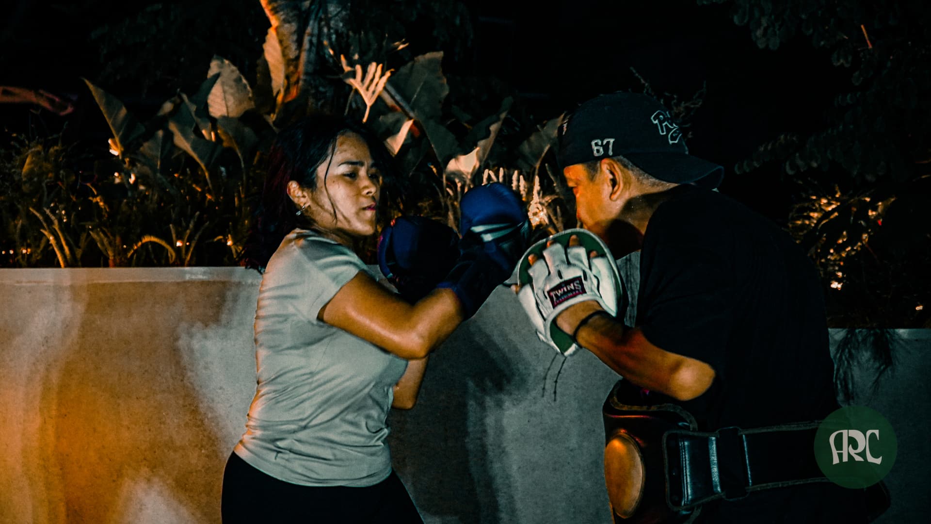 A member working pads with a coach at night
